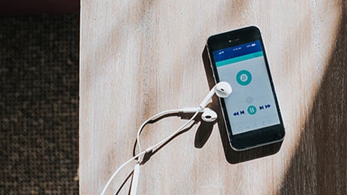 phone with music player open on screen and wired earphones 