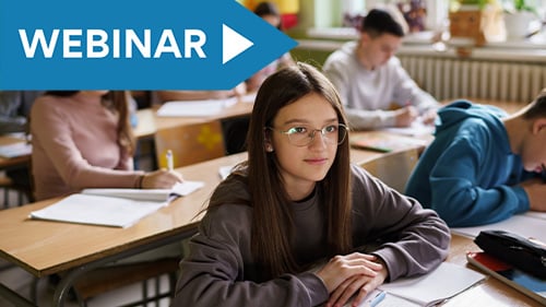 Middle school student sitting at desk watching the front of the classroom