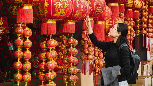 young woman looks at lanterns on street 