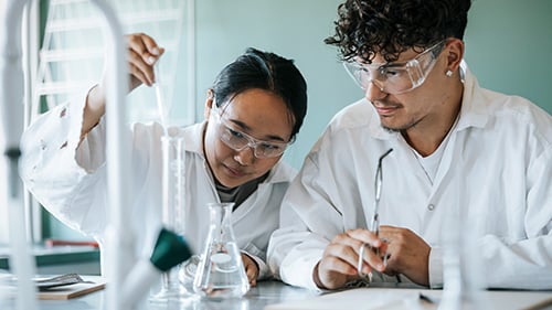 two high school students doing an experiment in a chemistry class