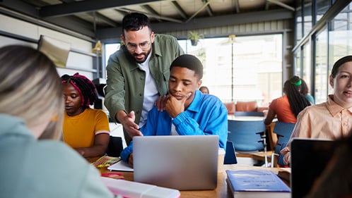 Teacher helps high school student understand something on laptop screen