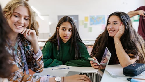 High school students collaborate around a laptop
