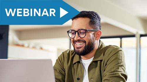 Man with glasses smiles at laptop screen