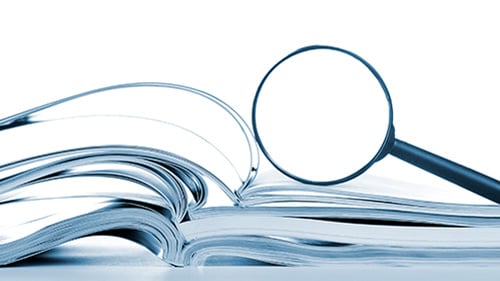 stack of books with magnifying glass sitting on top