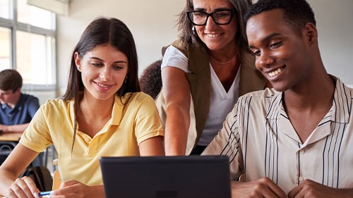 Teacher helping students with an assignment on a laptop 