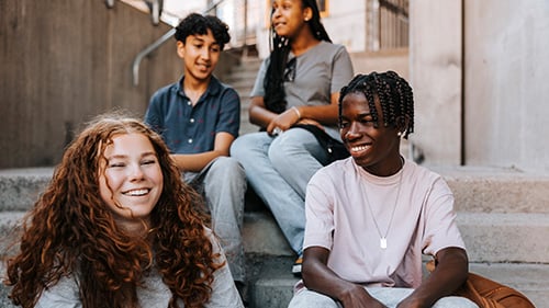 Middle school students sitting on concrete steps outside