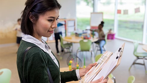 Teacher looking at data on a clipboard