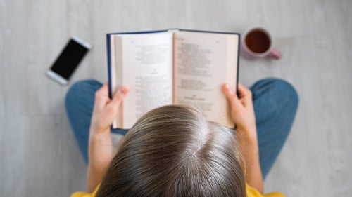 young girl reading from a poetry book