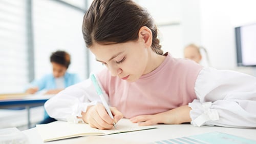 Middle school girl writes on paper