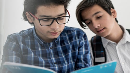 Middle school students look at book together