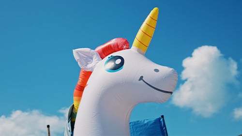 Inflatable unicorn against backdrop of blue sky and white clouds