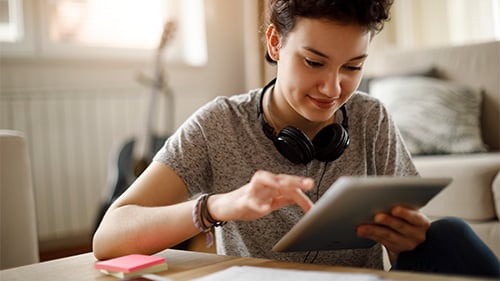 high school student using ipad has headphones around neck