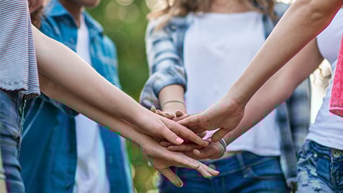 teenagers putting hands together