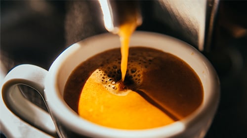 Pouring espresso into white espresso cup