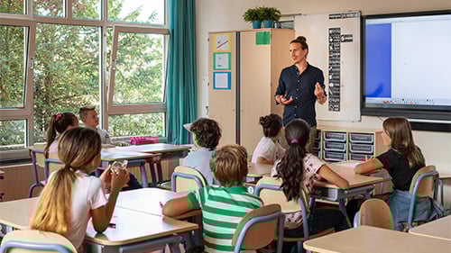 Teacher at the front of classroom speaking to class of elementary students