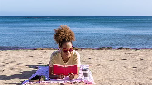 woman reading book on the beach