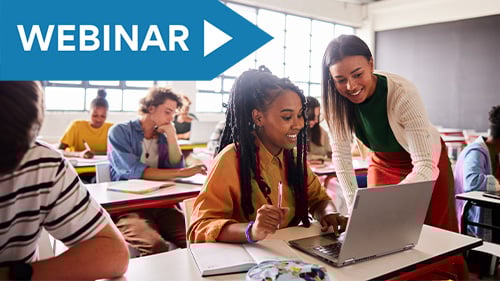 High school student looking at laptop with teacher