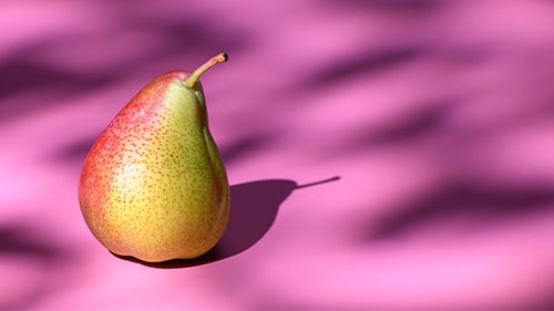 A pear and its shadow against a pink backdrop