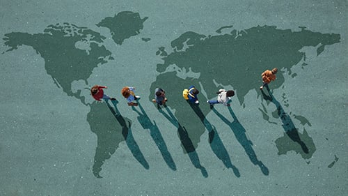 Students walking in line across a map of the world