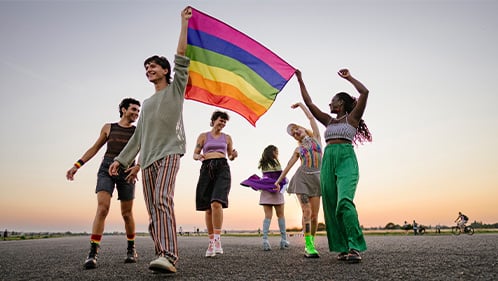 Group of teens outside waving a Pride flag