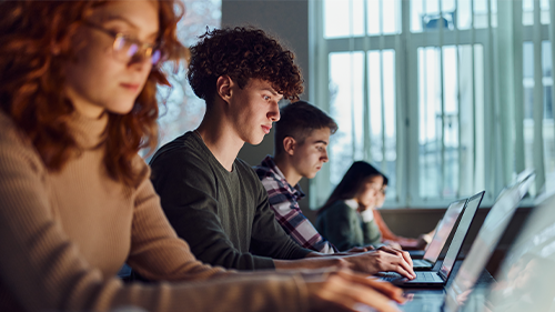 high school students writing on laptops