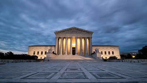 Federal judicial building lit up in the early evening under a cloudy sky