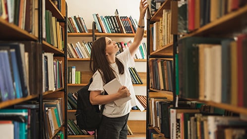teenage girl looks for a book in the library