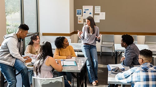 Teacher speaking to high school students in classroom