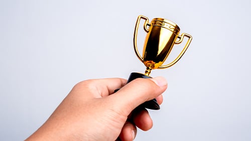 hand holding miniature trophy 