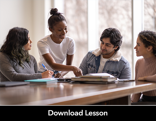 Four students sit around a book and discuss its contents