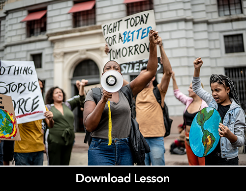 young protesters at a climate march hold up signs and fists. Many appear to be chanting. 