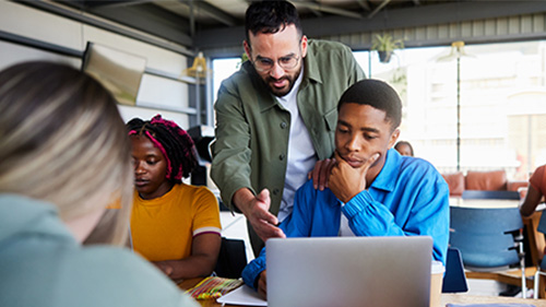 Teacher explaining something to student on computer