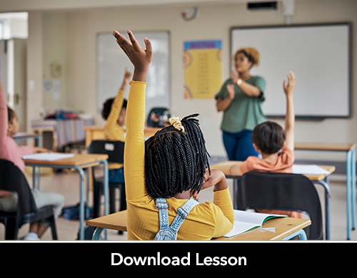 Elementary school students raising hands as teacher stands at front 